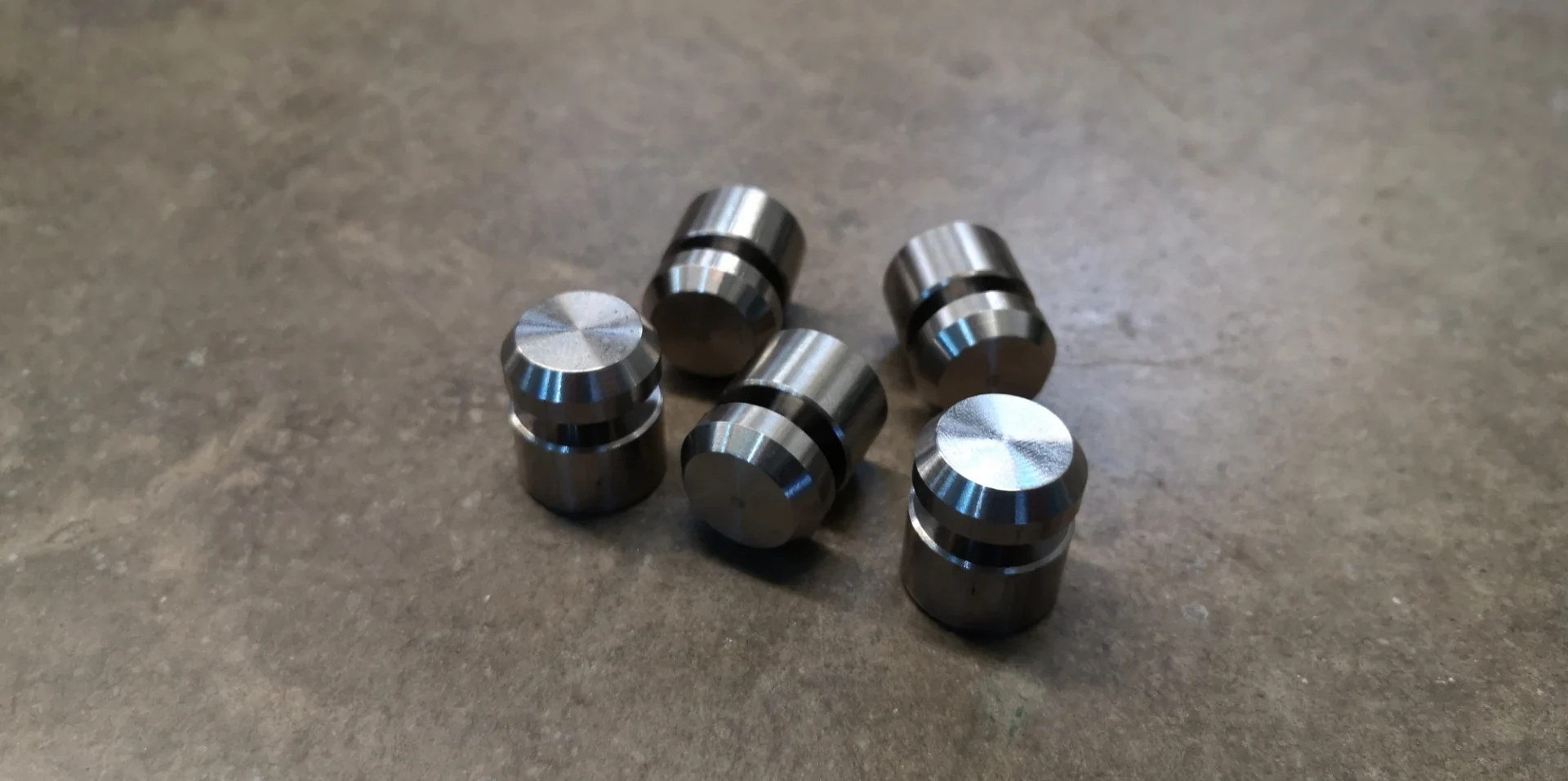 Five metal cylinders on a concrete surface.
