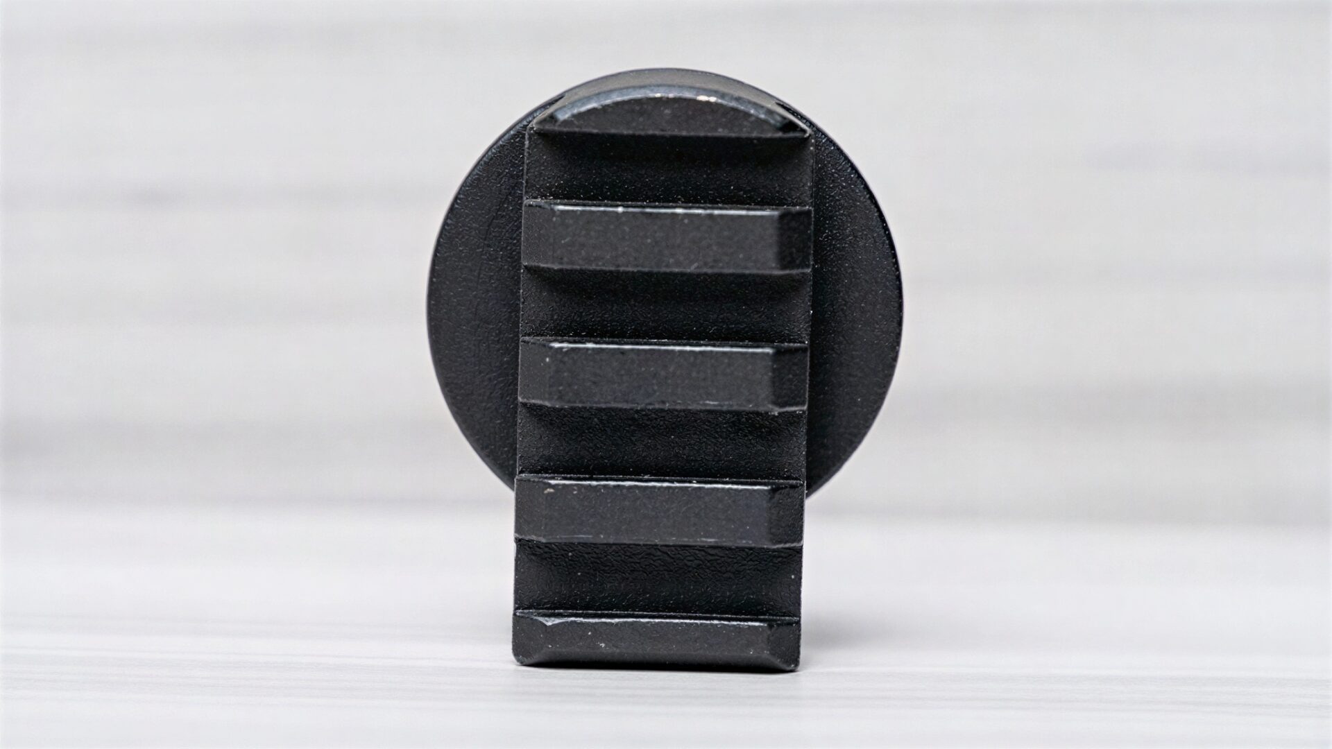 Black wall hook with vertical grooves.