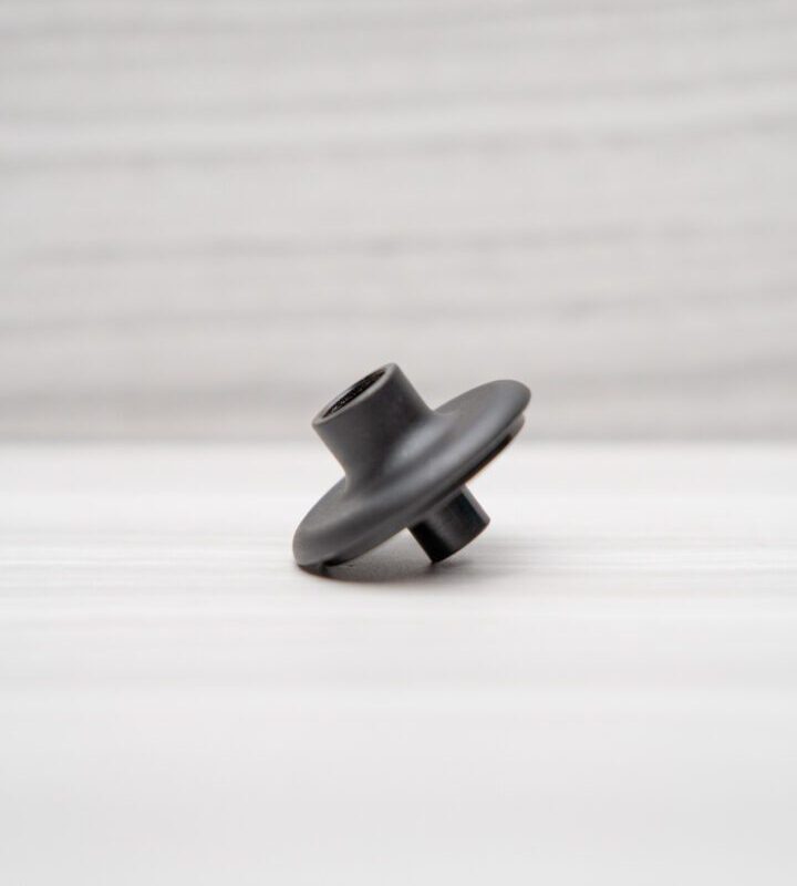 Black plastic part on white surface.