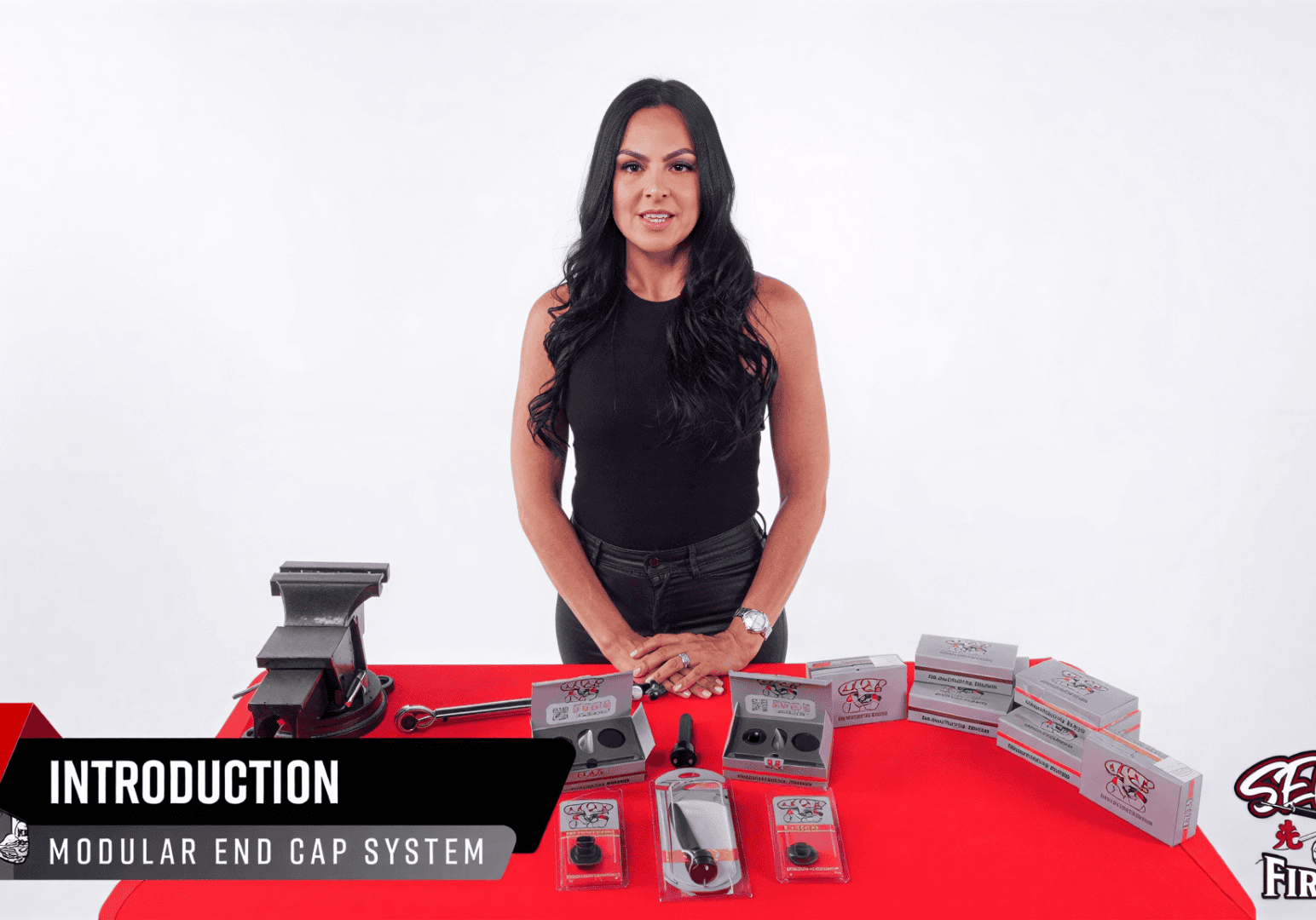 Woman presenting firearm accessories on table.