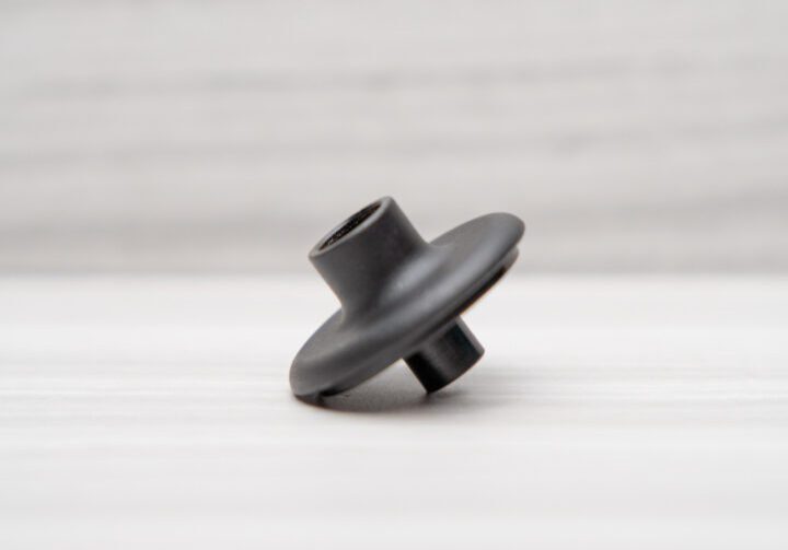 Black plastic part on white surface.