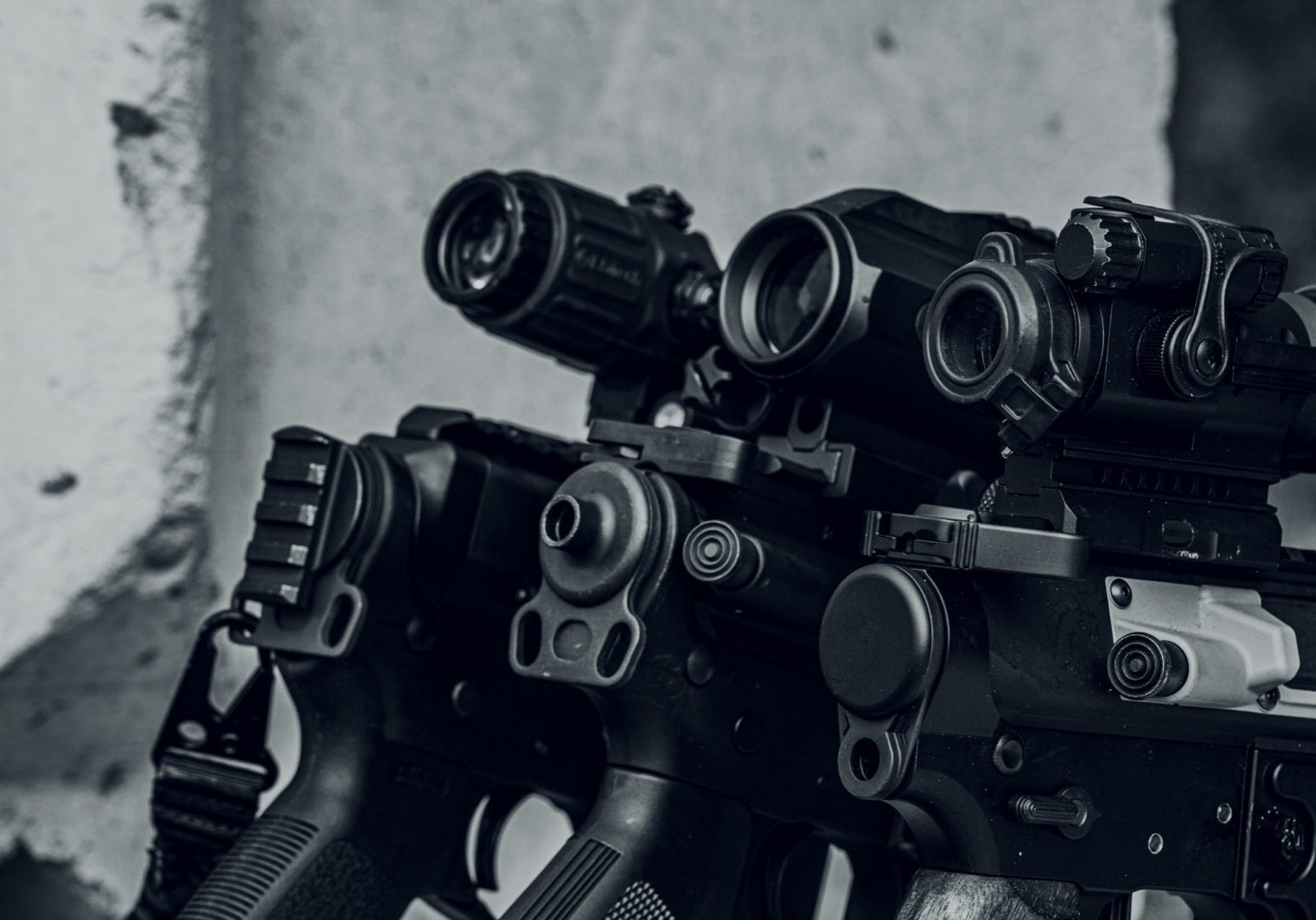 Rifles with scopes leaning against a wall.