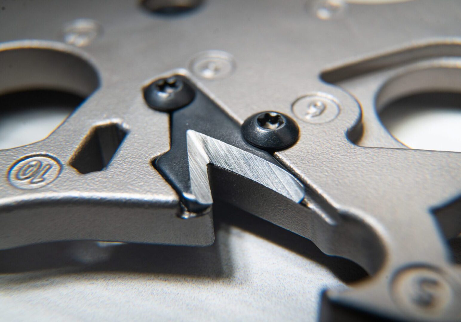Close-up of metallic mechanical component, screws visible.